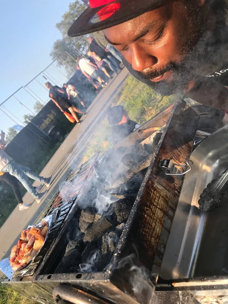 Joppe lutar sig över en rykande kolgrill på en festival